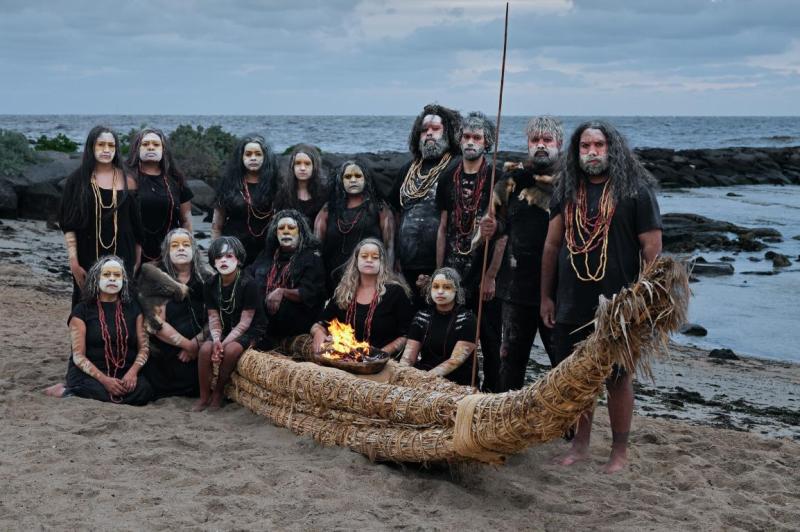 People stand by a traditional island boat next to the sea