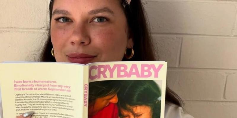 A woman looks over while reading her book 'Crybaby'