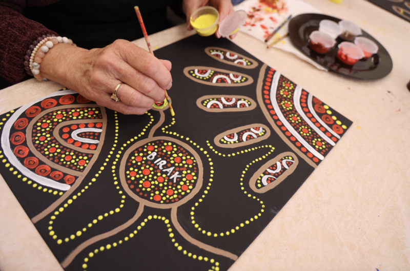 A hand paints a aboriginal artwork